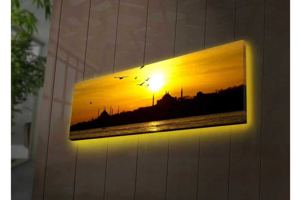 Lerretsbilde med LED-belysning 30x90 cm - Solnedgang over en bysilhuett med fugler i flukt v:6195381
